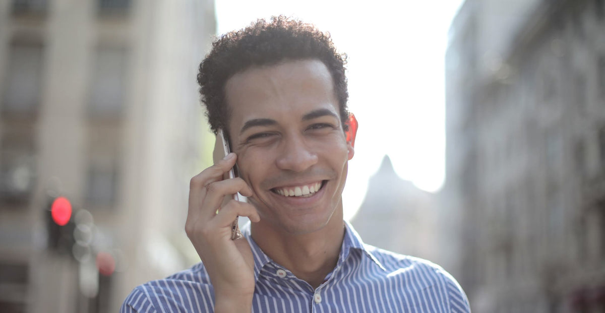 Smiling man talking on a mobile phone on a city street