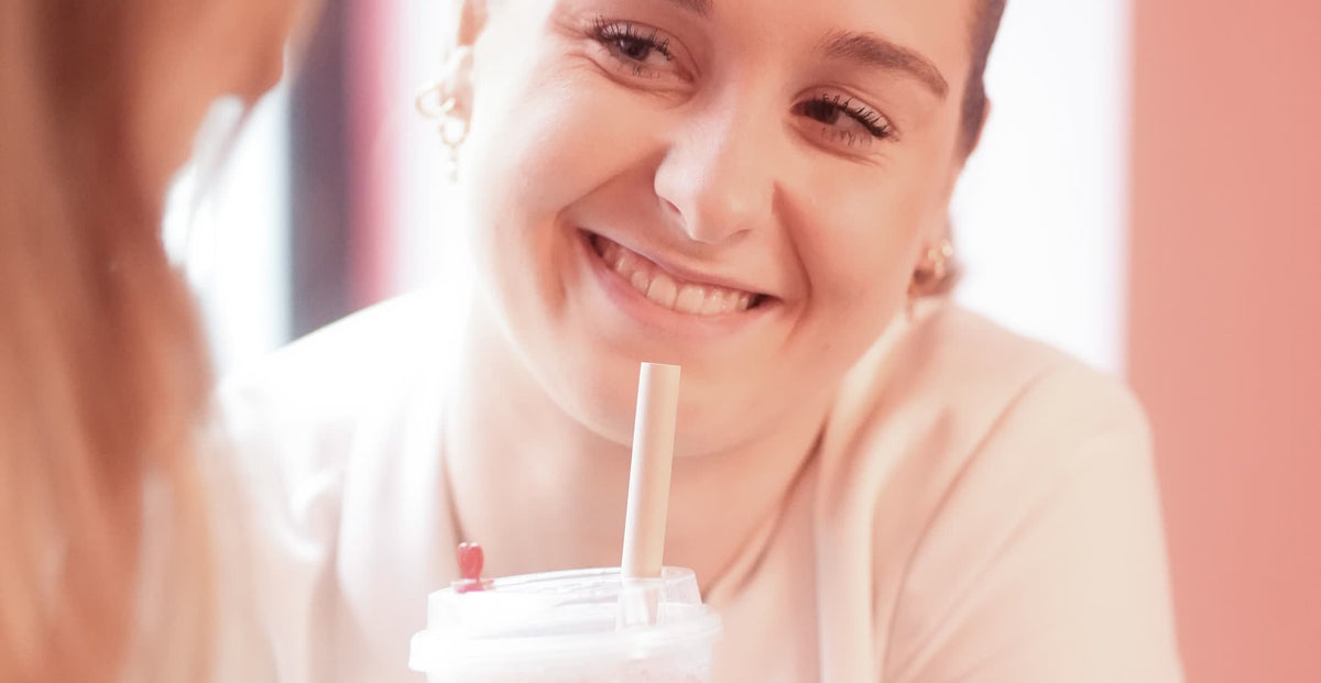 Smiling customer holding an iced bubble tea with a straw
