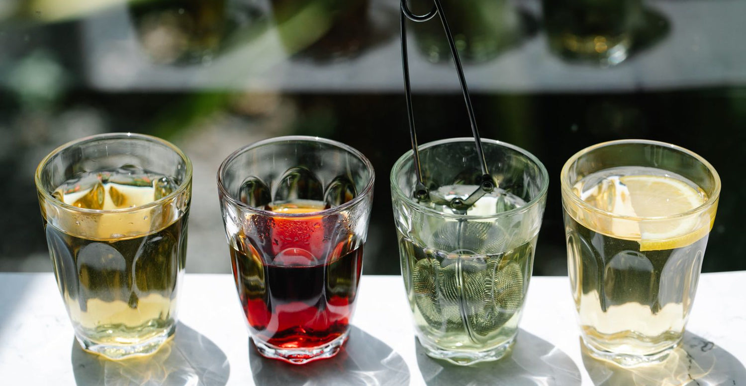 Four glasses of different coloured tea lined up for a blind taste test
