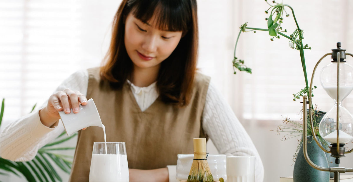 A woman pouring milk into a glass at a kitchen table